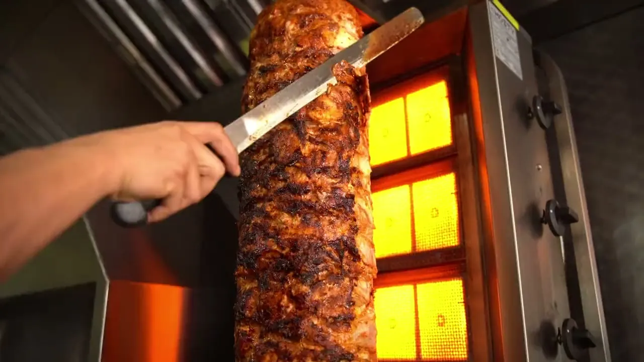 Döner being carved beside the vertical grill